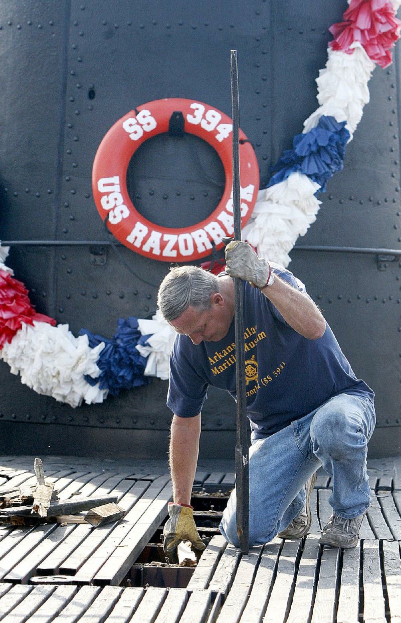 Executive Director Greg Zonner pulls up rotten timbers Saturday from the deck of the USS Razorback at the maritime museum on the North Little Rock side of the Arkansas River.