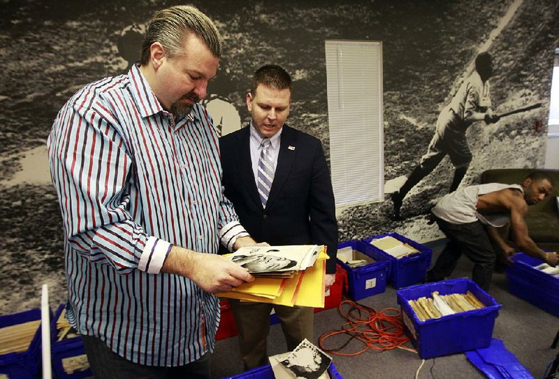 In this file photo, John Rogers, left, examines some of the over $2 million dollars of assets returned to his company Rogers Photo Archive, by Secret Service Task Force Officer Brandon Bennett, center, after 2 former employees stole the historic photos and sold them online.