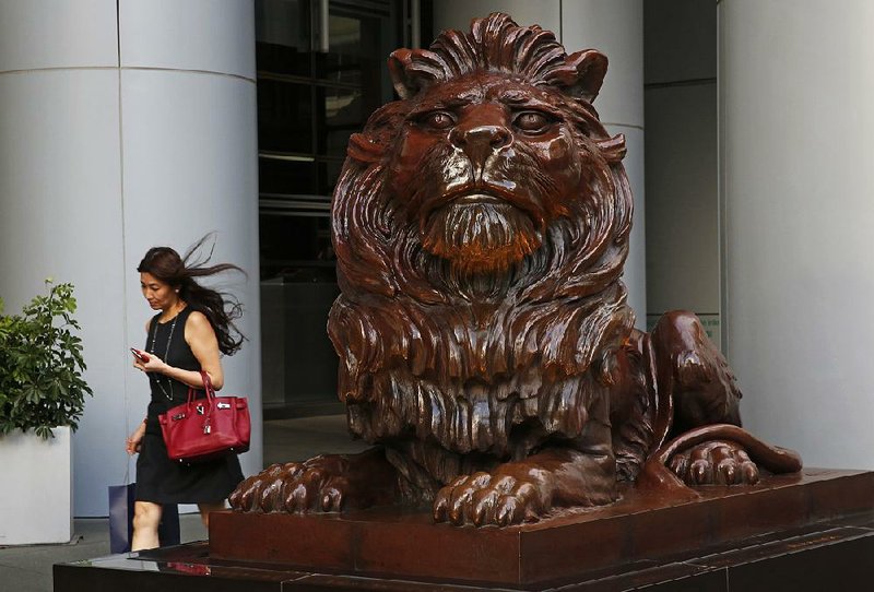 A woman passes the entrance of the HSBC building in Hong Kong on Tuesday. The bank said Tuesday that it will cut up to 25,000 jobs to reduce costs. 