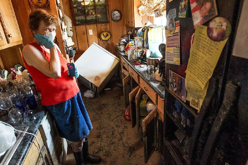 Donna Yarbro pauses from the messy cleanup of mud and water in her Pine Bluff home Tuesday as floodwaters from the Arkansas River recede from her Island Harbor Estates neighborhood.