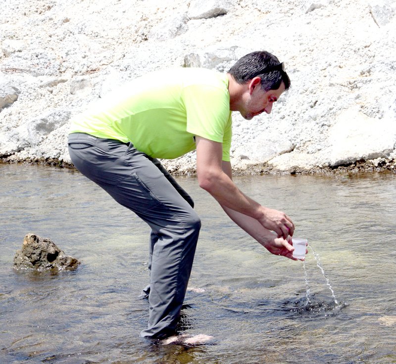 LYNN KUTTER ENTERPRISE-LEADER Dr. Brian Haggard, director of Arkansas Water Resource Center with University of Arkansas, takes a sample of water from a tributary that flows into the Illinois River. He sampled six sites located upstream and downstream from the sewer system that serves Valley View subidivision. This sample is being taken at the new bridge along Highway 170 in Prairie Grove. Haggard said he stands upstream when taking a sample so as not to contaminate the water.