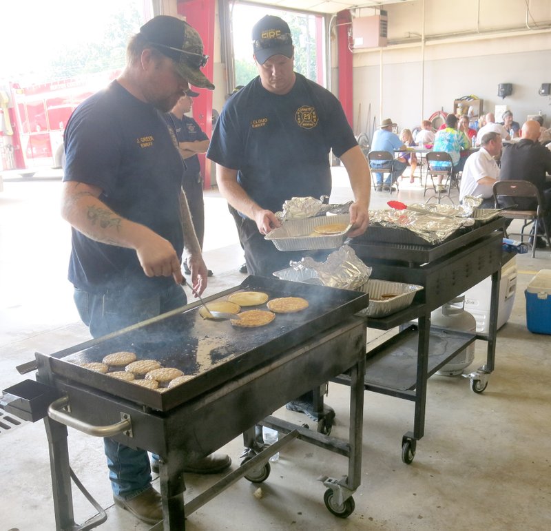 Photo by Susan Holland Gravette volunteer firefighters Josh Greer and Travis Cloud served as cooks Saturday morning when the Gravette Fire Department crew prepared and served breakfast to first Saturday guests.
