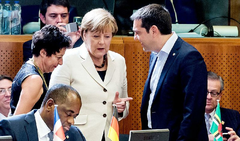 Greek Prime Minister Alexis Tsipras (right) visits Wednesday with German Chancellor Angela Merkel (center) at an economic summit in Brussels. 