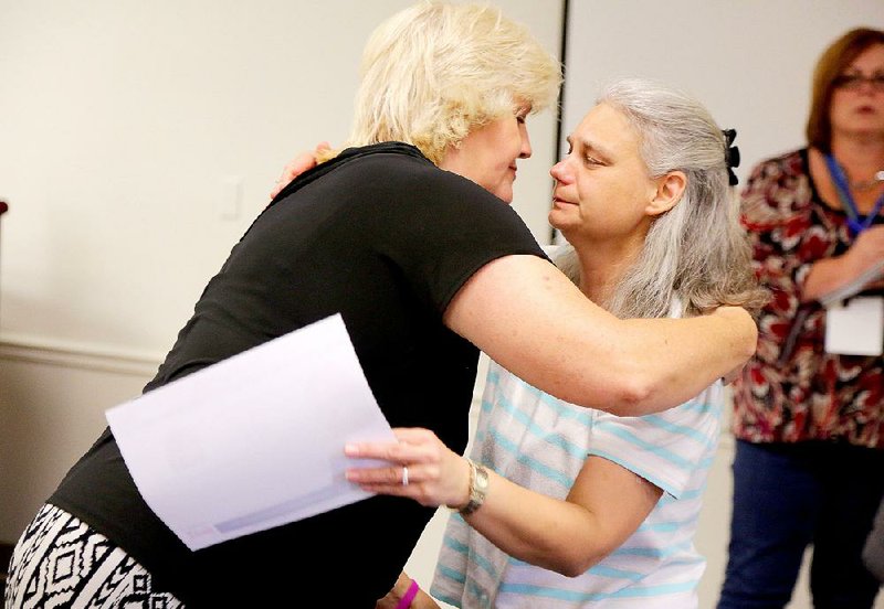 Colleen Nick (left) — whose daughter, Morgan, has been missing since 1995 — hugs Judy Compton — whose daughter, Cassie, disappeared from Stuttgart in September — as they take part Wednesday at the annual Never Forgotten: Arkansas Takes Action event, which unites families of missing people and law enforcement officials.