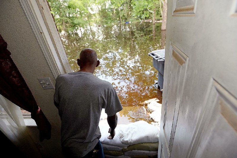 Arthur Walker looks out the back door of his flooded home Wednesday in Shreveport, where the Red River was finally starting to recede after cresting at 7 feet above flood stage. In Arkansas, teams were still waiting for the river to go down enough to access some areas. 