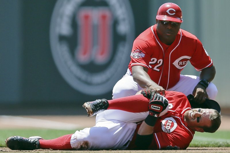 Cincinnati Reds' Zack Cozart winces in pain alongside first base coach Billy Hatcher after injuring his right leg running out a ground ball during the first inning of a baseball game against the Philadelphia Phillies, Wednesday, June 10, 2015, in Cincinnati. Cozart was helped off the field.