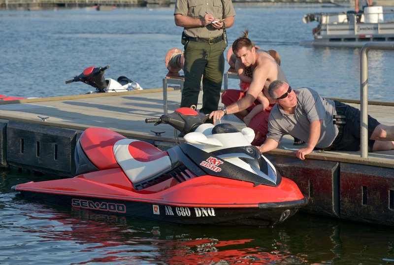 An Arkansas Game and Fish officer inspects a personal watercraft at Prairie Creek Marina after it was involved in a crash with another craft on Beaver Lake on Thursday June 11, 2015.