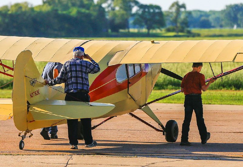 Gene Martin (center), owner of Martin Field in South Sioux City, Neb., helps instructor Scott Currie (left) and 12-year-old flight student Pierce Turner push an aircraft from its parking spot onto the runway. 