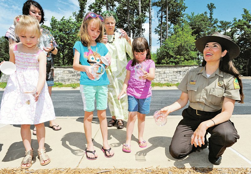 NWA Democrat-Gazette/ANDY SHUPE Rebekah Penny (right), a park interpreter at Hobbs State Park-Conservation Area, smiles Saturday as park visitors Brooklynn Zechiedrich, 5, (from left) of Rogers; Ashlee Belden, 7; and sister Jade Dowell, 5, of Pea Ridge release painted lady butterflies while enjoying programming at the park. The park will host events during the summer as a part of its Summer of Insects series. For more photos, go to www.nwadg.com/photos.