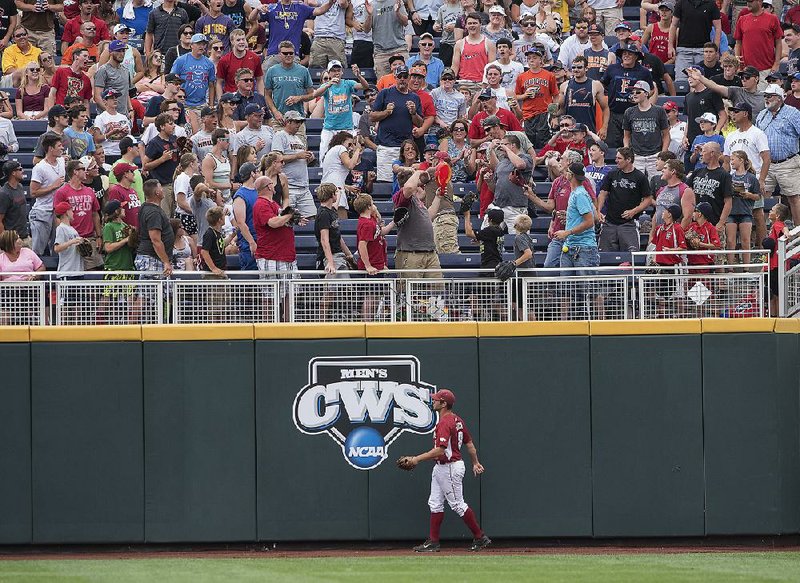 Arkansas outfielder Tyler Spoon watches fans fight for a home run ball hit by Virginia’s Joe McCarthy in the second inning. McCarthy’s shot was one of six two-out hits for the Cavaliers.