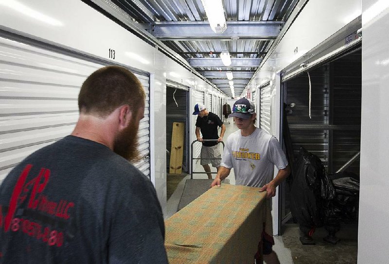 Workers with J&B Movers (from left) Haden Hawkins, Lukas Burrow and Michael Post move a client’s belongings Thursday at a storage facility in Maumelle. The startup, started by a college student, employs mostly students. 