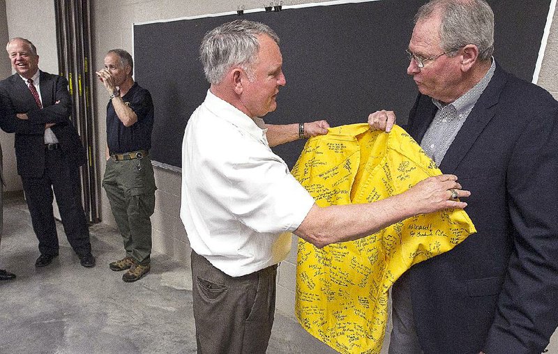 Pulaski County Sheriff Doc Holladay (center) presents Detention Chief Randy Morgan with an inmate shirt signed by county jail workers during a retirement ceremony last week to honor Morgan’s 17 years of overseeing operations at the jail. 