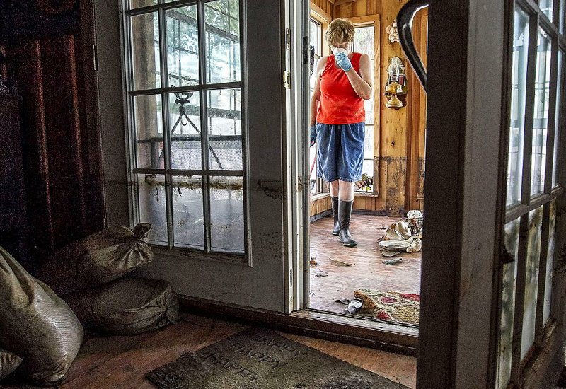 The high-water line is visible on living room doors as Donna Yarbro cleans mud and water from her home in Pine Bluff on Tuesday in the aftermath of a flood in the Island Harbor Estates neighborhood along the Arkansas River. 