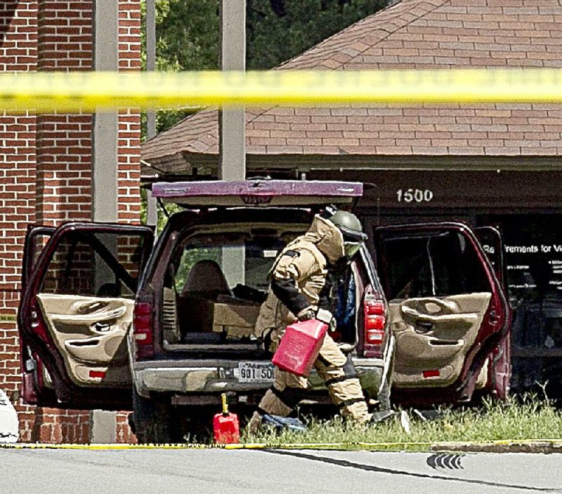 A man in a protective suit searches a Ford Expedition at the entrance to Little Rock Air Force Base in Jacksonville after base security airmen shot the driver, who was trying to force his way onto the base. 