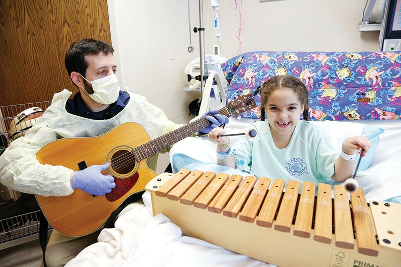 Arkansas Children’s Hospital music therapist Andrew Ghrayeb makes music with patient Kylee McCray.