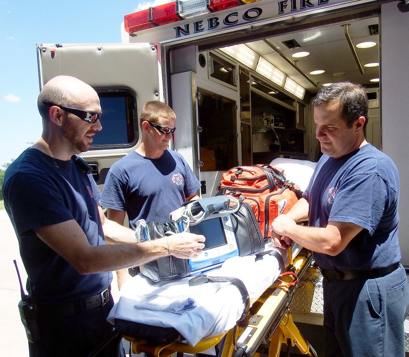 TIMES photograph by Annette Beard Andy Driggs and Zack Oldebeken, emergency medical technicians, and Cleve Carter, paramedic, look over some of the equipment in the advanced life support ambulance at NEBCO. The ambulance service celebrates five years as an advanced life support ambulance this year.