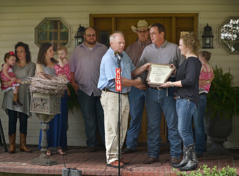 NWA Democrat-Gazette/BEN GOFF Jim Singleton (front, from left), head of the Benton County Farm Bureau selection committee, presents the Benton County Farm Family of the Year award to Brent Butler and wife Ronda Butler on Monday at the Butler home in Siloam Springs.