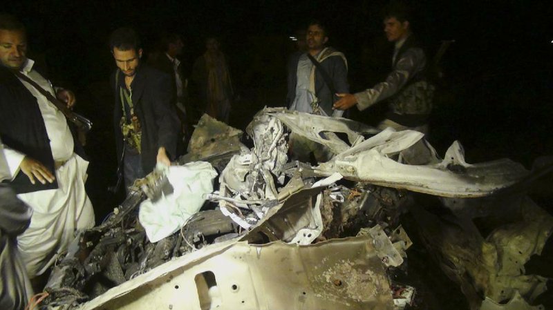 Shiite rebels look at the wreckage of a vehicle at the site of a car bomb attack Wednesday in Sanaa, Yemen.