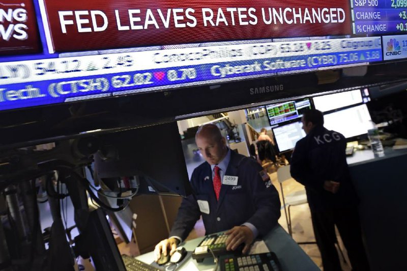 A television screen shows the Federal Reserve’s decision on interest rates Wednesday as specialist John Parisi works on the floor of the New York Stock Exchange. 