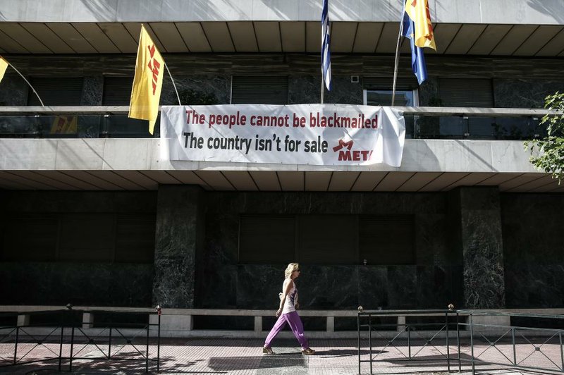A woman passes a banner placed by a leftist group at the offices of the European Union in Athens, Greece, on Wednesday. 