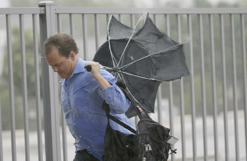 Bill Buehring’s umbrella is caught in a gust of wind Wednesday from Tropical Depression Bill in Arlington, Texas. Though slowing and weakening, the storm still was packing a lot of rain.