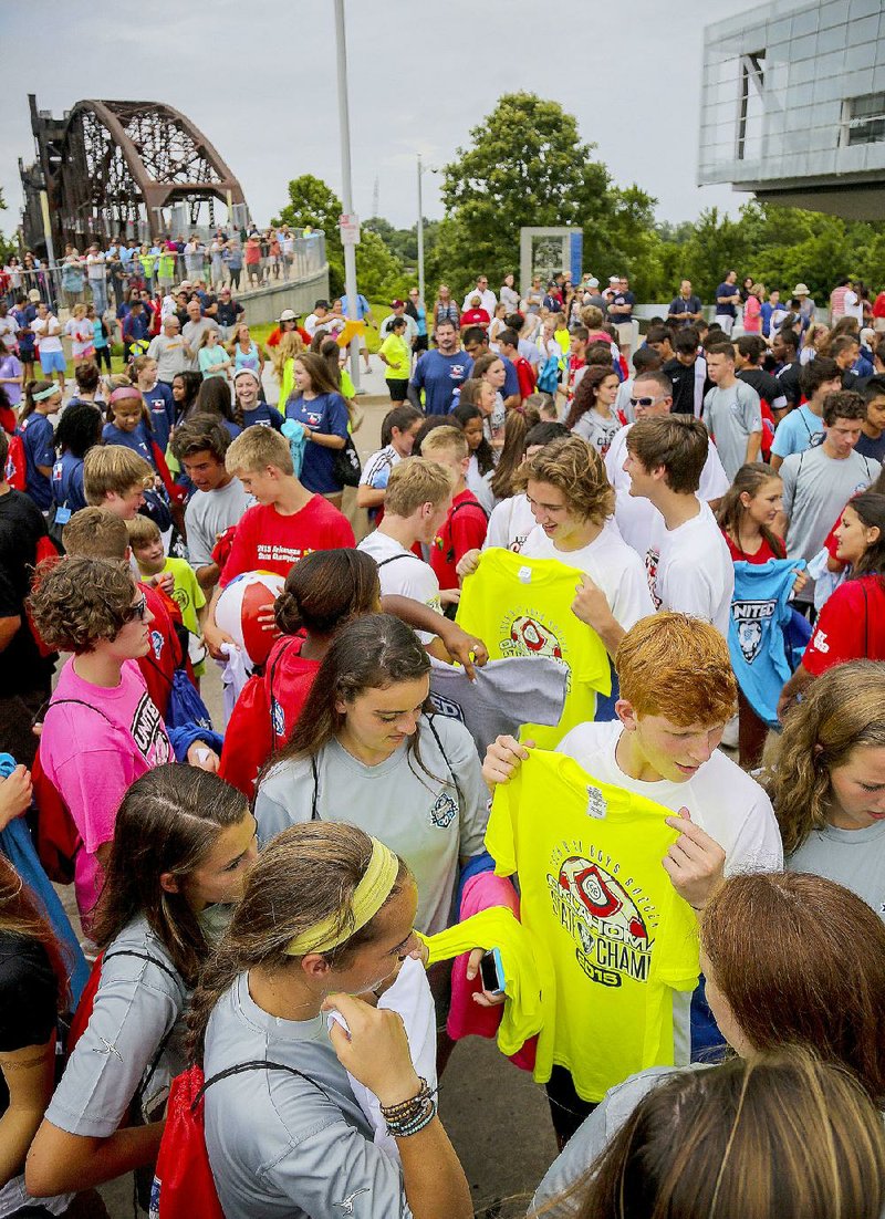 Tulsa Soccer Club’s Tyler Tregoning (bottom right) holds up a T-shirt for trade among a group of players from Tennessee during a pin and T-shirt swap Thursday outside the Clinton Presidential Center in Little Rock during opening ceremonies for this weekend’s U.S. Youth Soccer Region 3 championships, which will be held at North Little Rock’s Burns Park and Little Rock’s Otter Creek Park.