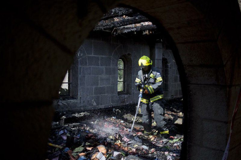 An Israeli firefighter extinguishes embers after a fire caused heavy damage to the Church of Multiplication of Loaves and Fish near the Sea of Galilee in Tabgha, Israel, on Thursday. 