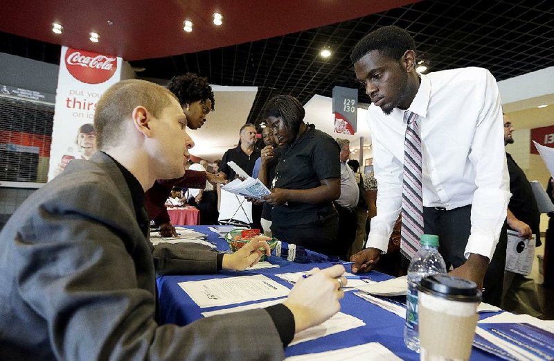 Job seeker Cory McClain (right) listens to Teleperformance employee Sam Cucci at a job fair last week in Sunrise, Fla. Applications for unemployment aid dropped 12,000 last week to a seasonally adjusted 267,000, the Labor Department said Thursday. 
