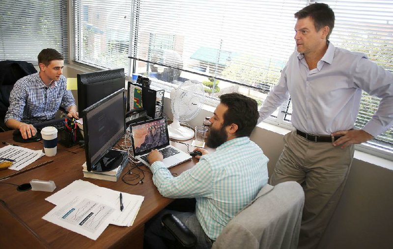 Judd Hollas (from right), president and CEO of EquityNet, Adam Vanderbush, chief marketing officer, and Patrick Moss, public relations manager, work in their Fayetteville office earlier this month. EquityNet, established in 2005, is a business crowd-funding platform.