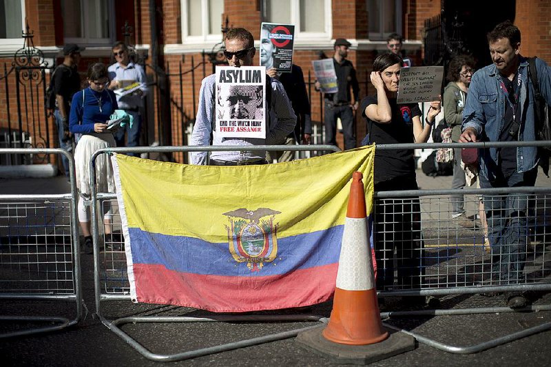 Supporters of WikiLeaks founder Julian Assange hold placards and stand behind an Ecuadorean flag during a vigil across the street from Ecuador’s embassy in London on Friday. 