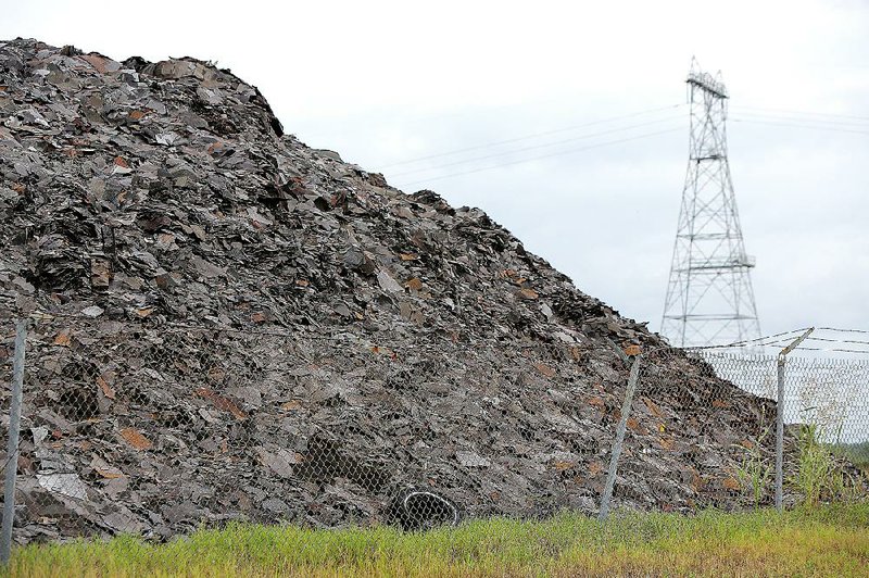 A large pile of roofing shingles sit Friday behind a fenced area along Industrial Harbor Road in the The Port of Little Rock area. The Little Rock Port Authority is looking for ways to dispose of about 45,000 cubic yards of roofi ng shingles. 
