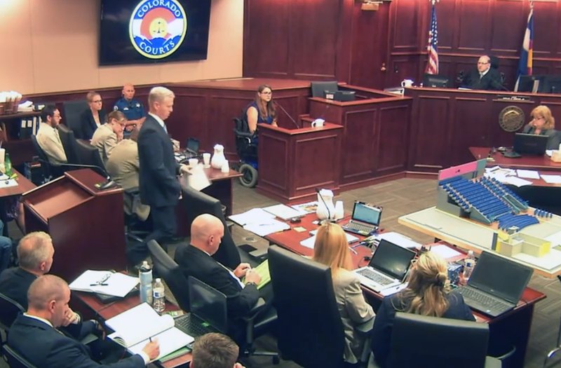 In this image taken from video, Ashley Moser, center top, who lost her 6-year-old daughter Veronica, was paralyzed, and suffered a miscarriage in the 2012 Colorado movie theater mass shooting, testifies during the trial of theater shooter James Holmes, pictured at top left, in Centennial, Colo., Friday, June 19, 2015. With Moser's testimony, the prosecution rested its case, led by District attorney George Brauchler, pictured fifth from left standing. 