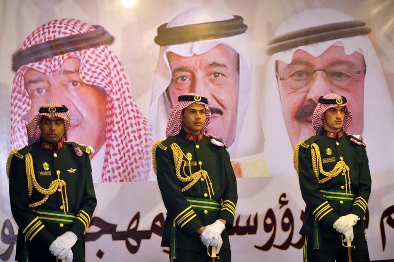 In this Feb. 18, 2014 file photo, Saudi royal guards stand on duty in front of portraits of King Abdullah bin Abdulaziz, right, then Crown Prince Salman bin Abdulaziz, center, and Muqrin bin Abdulaziz during a culture festival in Riyadh, Saudi Arabia. WikiLeaks is in the process of publishing more than 500,000 Saudi diplomatic documents to the Internet, the transparency website said Friday, June 19, 2015.