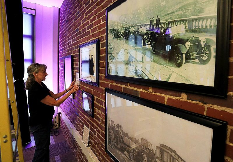 Sandra Taylor Smith on Thursday places information cards around photos taken during the construction of the Broadway Bridge. An exhibit on the bridge opened Friday at the Heritage Center in North Little Rock.