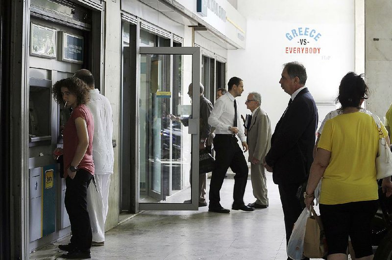 People use the ATMs on Friday at a bank in Athens, Greece. Uncertainty about the country’s future with the euro currency has led Greeks to withdraw $34 billion from banks since December. 