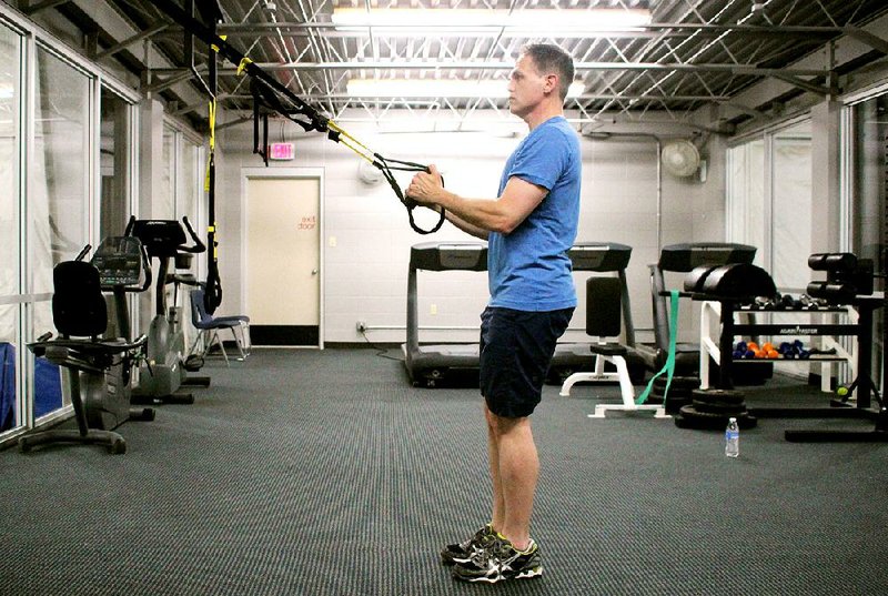 Ronnie Stone does step 1 of the TRX Lunge Row, a modification of the traditional lunge that takes a little pressure off the knees and hips as the exerciser uses upper body strength to supplement the work done by leg muscles.