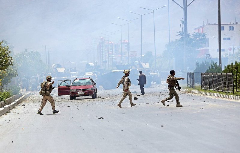 Afghan security troops gather at the site of a suicide attack during clashes with Taliban fighters in front of the Parliament in Kabul, Afghanistan on Monday.