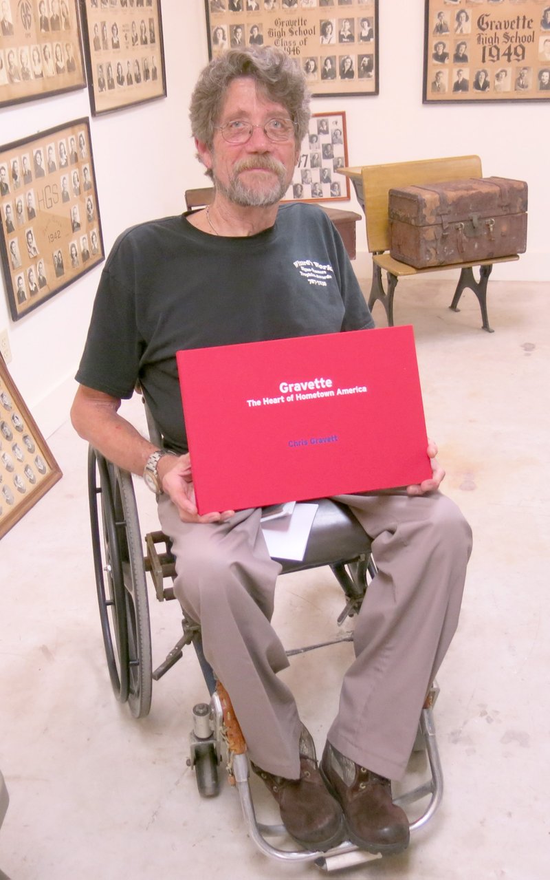 Photo by Susan Holland Gravette Museum commissioner Mike von Ree poses with the book &#8220;Gravette, The Heart of Hometown America,&#8221; after opening the package containing the volume at the June 1 museum commission meeting. The &#8220;coffee table&#8221; photobook is a documentary of author Chris Gravett&#8217;s perceptions of Gravette. Gravett published the book to fulfill requirements for his bachelor&#8217;s degree in photography at the University of Westminster in London.