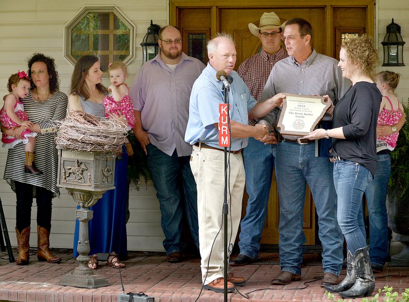 Photo by Ben Goff Jim Singleton, head of the Benton County Farm Bureau selection committee, presents the Benton County Farm Family of the Year award to Brent Butler and wife Ronda Butler, surrounded by family, on Monday, June 15, at the Butler home in Siloam Springs.