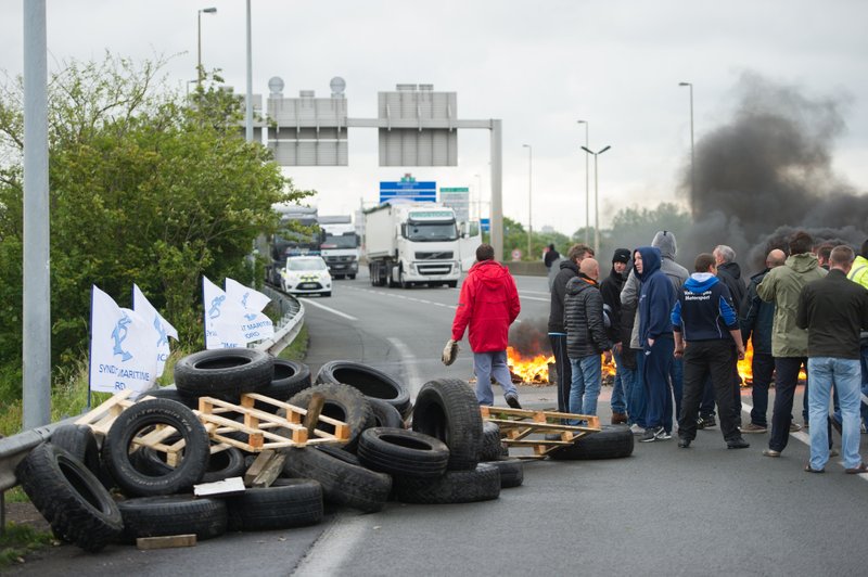 Striking ferry workers burn tyres as they block a ramp leading into the Eurotunnel before being dispersed by riot police in Calais, northern France, Tuesday, June 23, 2015. A strike by workers in the northern French port of Calais has left all passenger ferry service between the city and the English city of Dover suspended and briefly slowed traffic in the Eurotunnel. 