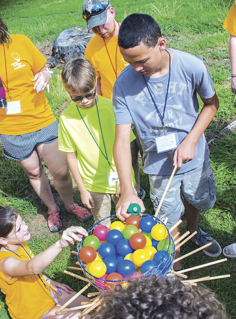 Sutton, 14, pulls a stick and tries not to dump the balls in a game of Ker Plunk during a session at Camp Quality, which allows children with cancer, along with their families, an opportunity to enjoy summer away from home and not think about their disease. Camp Quality is held at Camp Powderfork in Bald Knob.