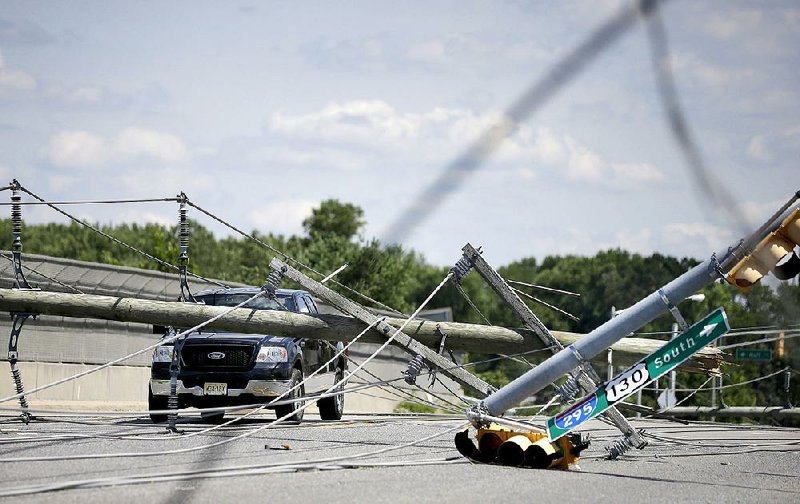 A  truck sits abandoned among downed electrical poles and wires Wednesday after a storm passed through Tuesday night in Gibbstown, N.J.