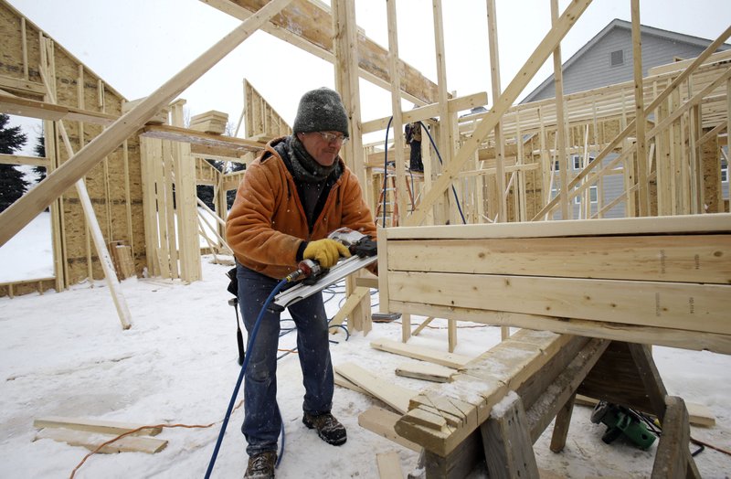 In this Wednesday, Feb. 18, 2015, photo, carpenter Joe Tominc cuts wood for a post on a new construction home in Pepper Pike, Ohio. The Commerce Department issues its last of three estimates of how the U.S. economy performed in the January-March quarter on Wednesday, June 24, 2015. 