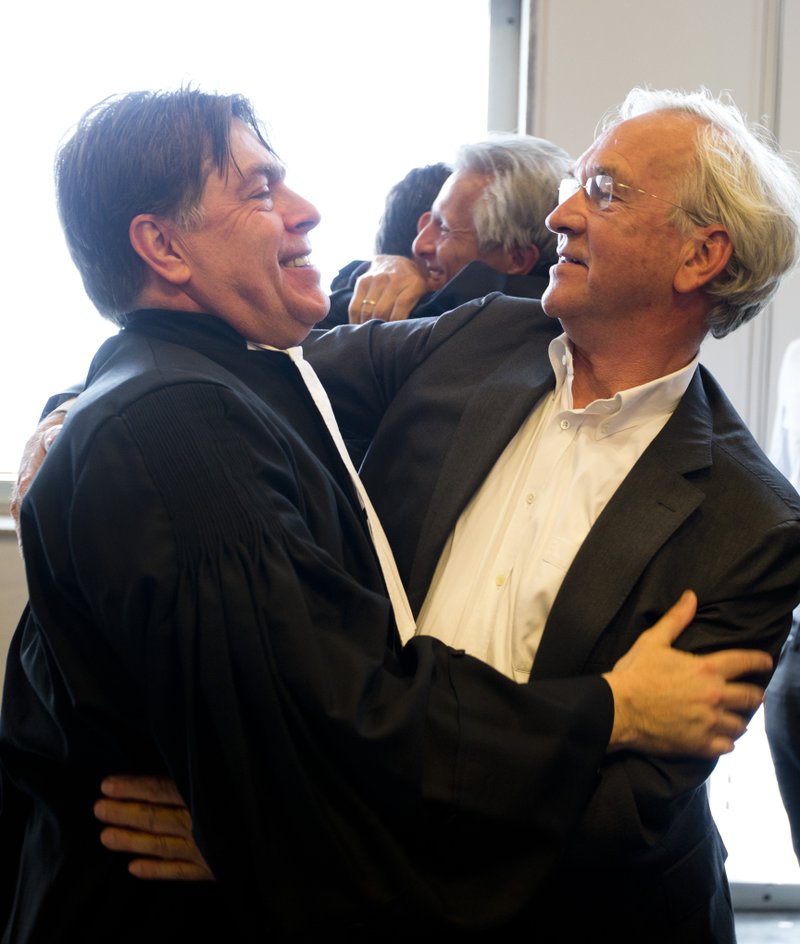 Urgenda Foundation lawyer Koos van der Berg, left, is congratulated after a Dutch court ordered the government to cut the country's greenhouse gas emissions by at least 25 percent by 2020 in a groundbreaking climate case that activists hope will set a worldwide precedent in The Hague, Netherlands, Wednesday, June 24, 2015. 