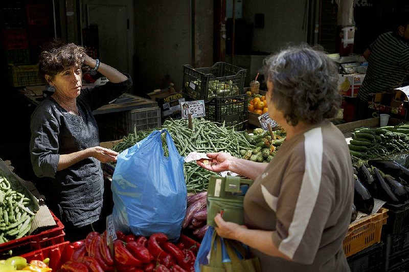 A woman buys fruit with euros Thursday at a market in Athens. A meeting of eurozone finance ministers ended Thursday without agreement on a rescue package for Greece. 