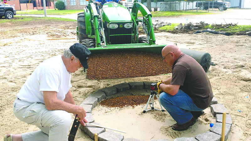 Duke Webb, left, and Sonny Ekdahl level the center space of the labyrinth before pea gravel is poured. The spirals combined with the circles represent a journey into one’s center and back into the world.