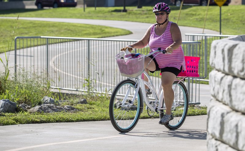 NWA Democrat-Gazette/JASON IVESTER Lisa Heffron of Rogers rides Thursday along the Razorback Greenway with her three-year-old Chihuahua Gidget in Rogers. On Saturday, bike riders are encouraged to take part in the Greenway to the LPGA, a ride that will run from the Bentonville Activity Center to the John Q. Hammons Center in Rogers to watch the Walmart NW Arkansas Championship golf tournament.