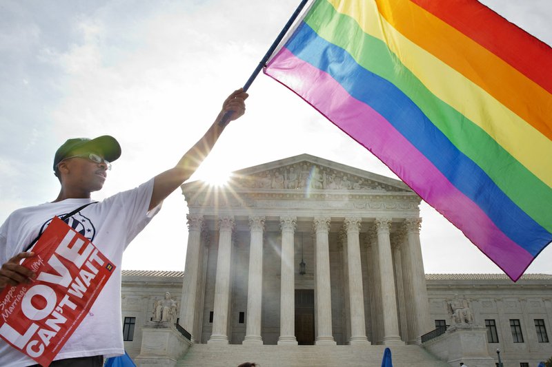 Carlos McKnight of Washington, waves a flag in support of gay marriage outside of the Supreme Court in Washington on Friday June 26, 2015. A major opinion on gay marriage is among the remaining to be released before the term ends at the end of June. 