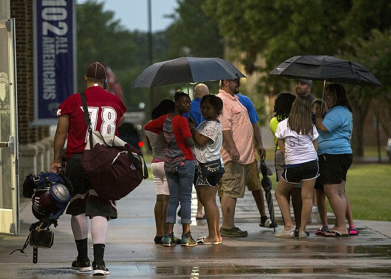 The West team’s Dakota Barrett of Mount Ida (left) walks toward the exit of Estes Stadium in Conway after the Arkansas High School Coaches Association All-Star football game was cancelled Friday night because of severe weather.