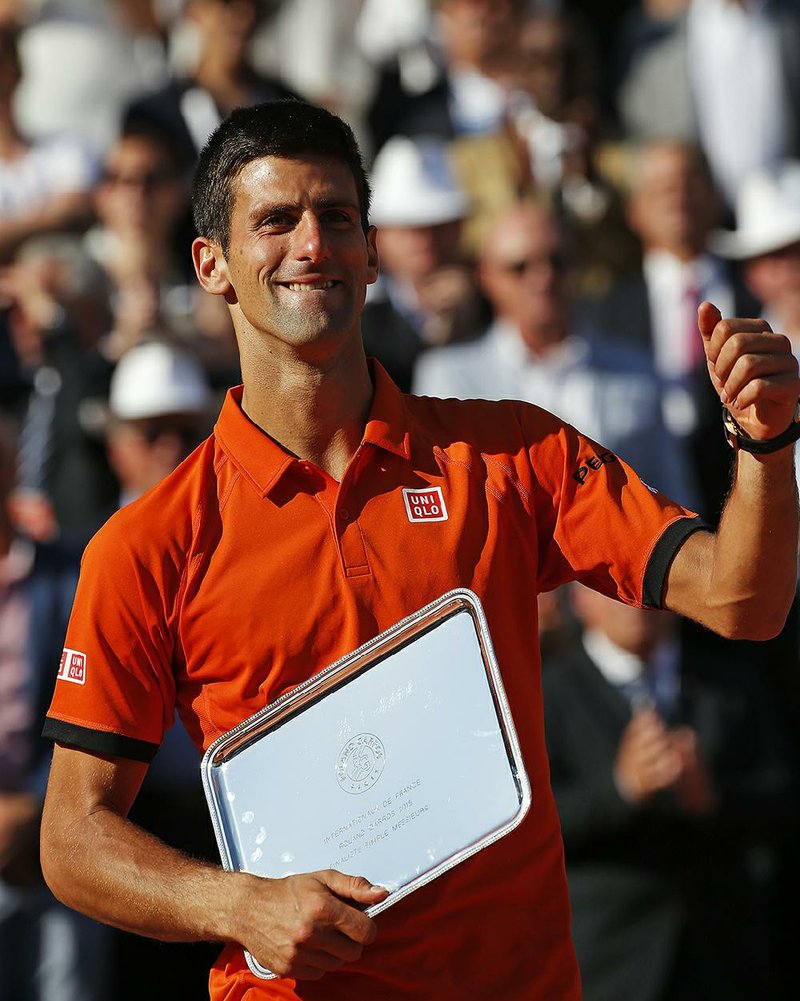 Serbia's Novak Djokovic gives a thumbs up as he holds the runner-up trophy after the men's final of the French Open tennis tournament which was won by Switzerland's Stan Wawrinka in four sets, 4-6, 6-4, 6-3, 6-4, at the Roland Garros stadium, in Paris, France, Sunday, June 7, 2015. 